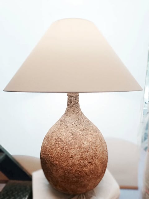 Table lamp with textured cork bulbous base and cream-colored fabric cone shade